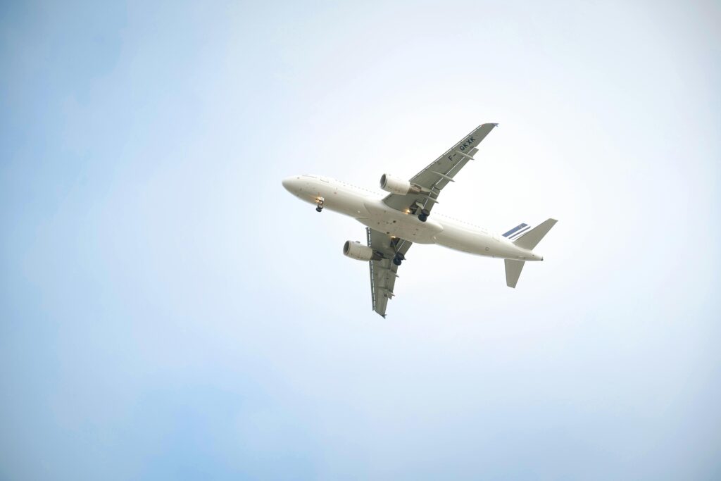 A white commercial airplane flying high against a clear blue sky, showcasing aviation dynamics.