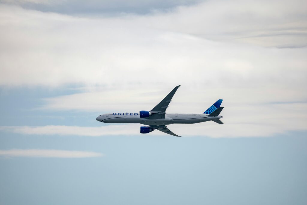 A United airplane soaring in the sky amidst clouds, showcasing modern aviation.